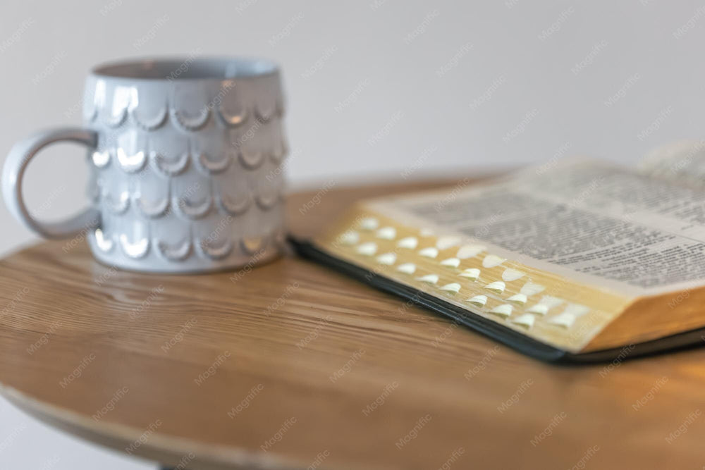 Aufgeschlagene Bibel und Tasse auf einem Tisch am Morgen