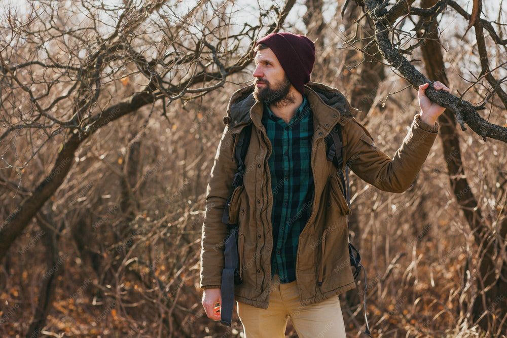 Mann mit Mütze und Rucksack auf einem Waldweg im Herbst