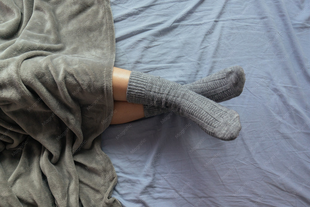 Füße in warmen Socken unter einer Decke – christliche Socken als Geschenk