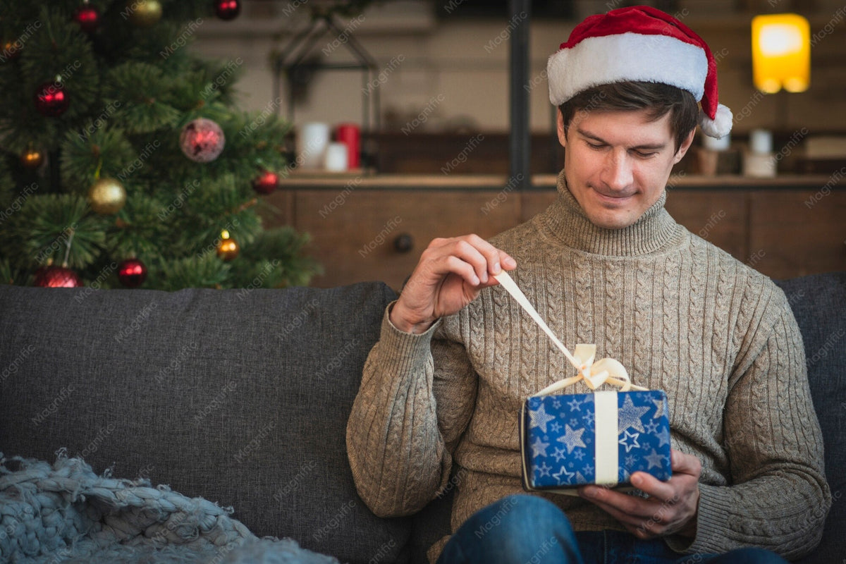 Mann im Pullover öffnet ein Geschenk – christliche Geschenke für Männer von Good-Natured